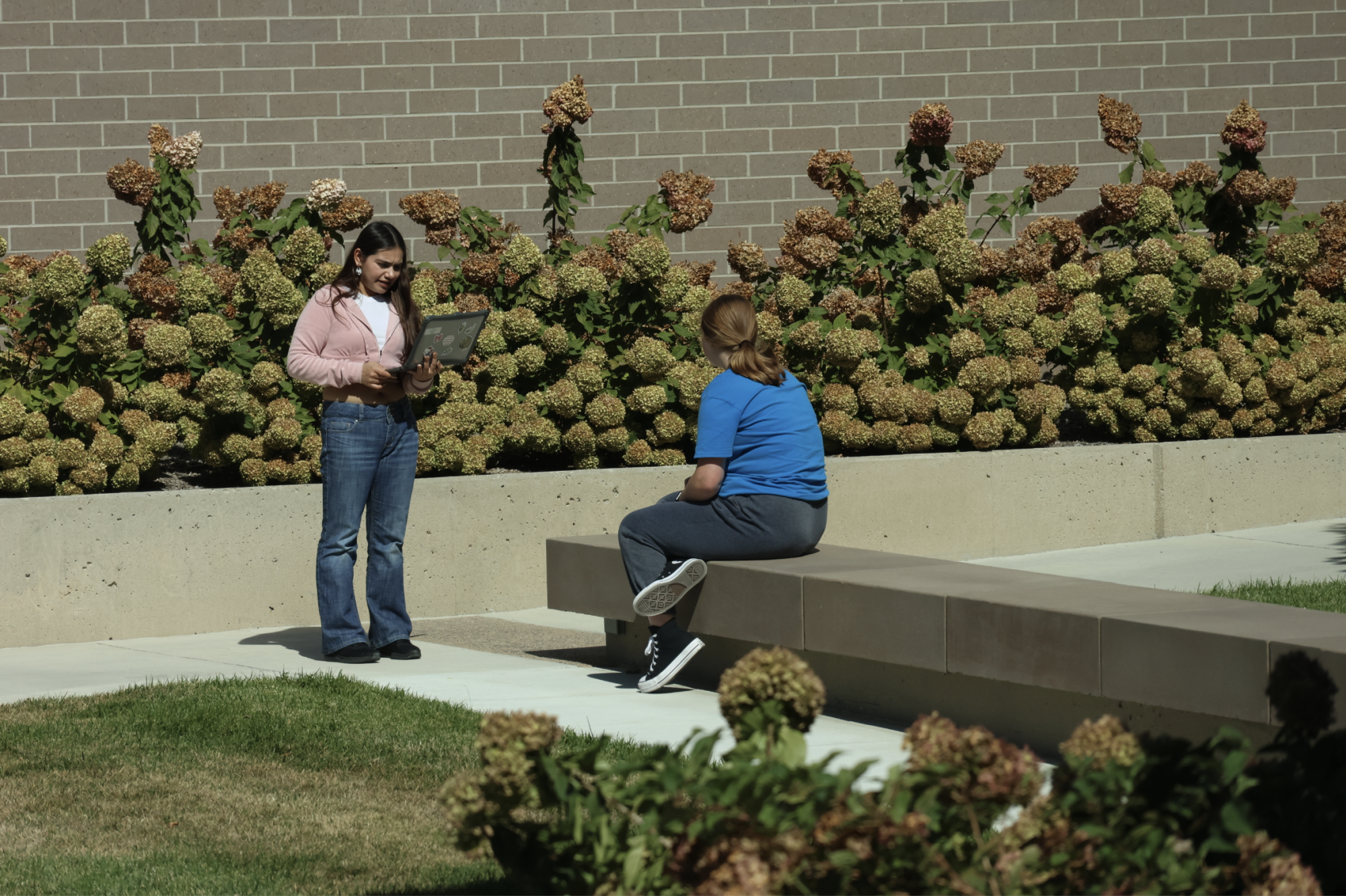 Speaking aloud, senior Kathryn Albarran practices her informative speech for junior Kristin Tuff in the courtyard on Oct. 4 for their Dual Credit Public Speaking class.